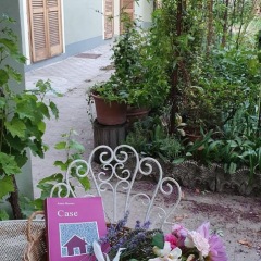 Il libro "Case" appoggiato su una sedia di metallo in un giardino
