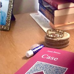 Il libro "Case" su una scrivania a fianco di libri e un burrocacao